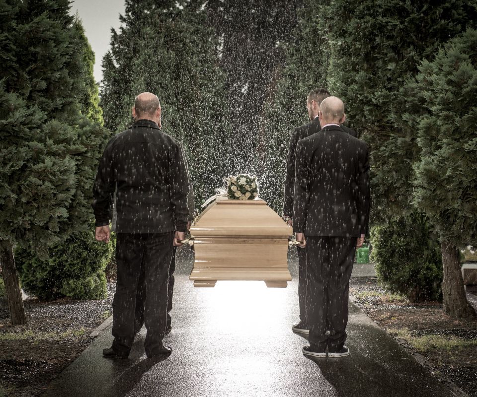 Sargträger tragen einen Sarg bei Regen